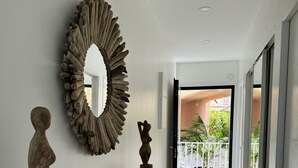 A hallway with a wooden bench, a large decorative mirror, and a sculpture.
