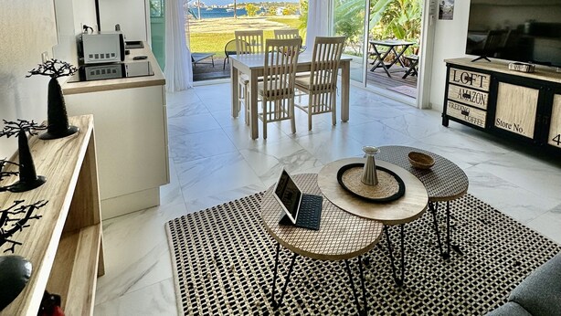 A modern living room with a ceiling fan, a TV, and a dining area with chairs and a table.