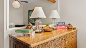 Un comptoir en bois surmonté d’un panier tressé contenant des fruits, de deux lampes et de jeux de société.