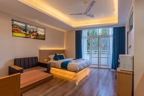 A modern hotel room with a bed, a seating area, a ceiling fan, and a large window with curtains. - Pokhara Apartments Inn (Pokhara)
