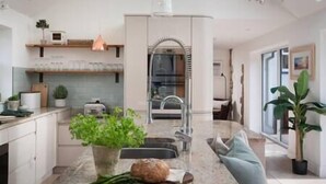 Een moderne keuken met een centraal eiland, inbouwapparatuur en een groot raam.