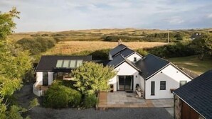 Een modern huis met een ruime oprit, een overdekt terras en uitzicht op het omliggende landschap.