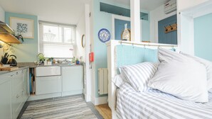 A compact bedroom with a bed, a window, and a kitchenette. - Zawn Nook (Falmouth)