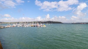 A marina with multiple boats docked, calm water, and a clear sky. - Zawn Nook (Falmouth)