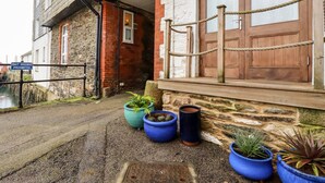 A building with a stone facade, a wooden door, and a sign prohibiting bait digging. - Zawn Nook (Falmouth)