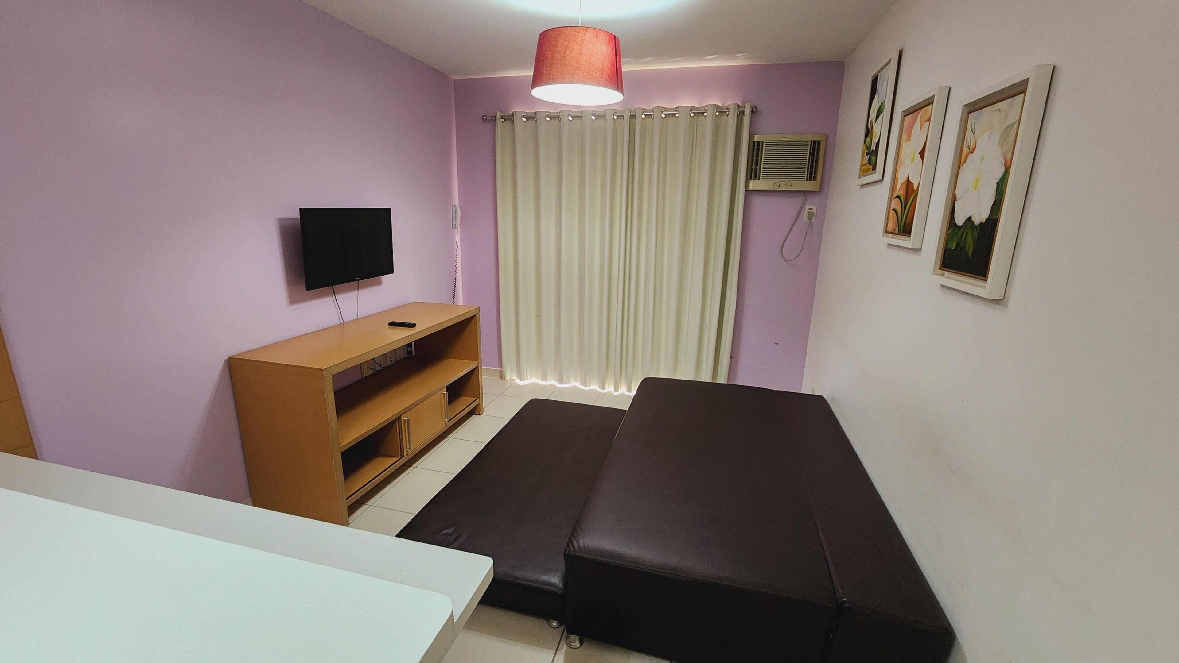Une chambre avec un lit, une télévision, une armoire en bois et une fenêtre avec des rideaux.