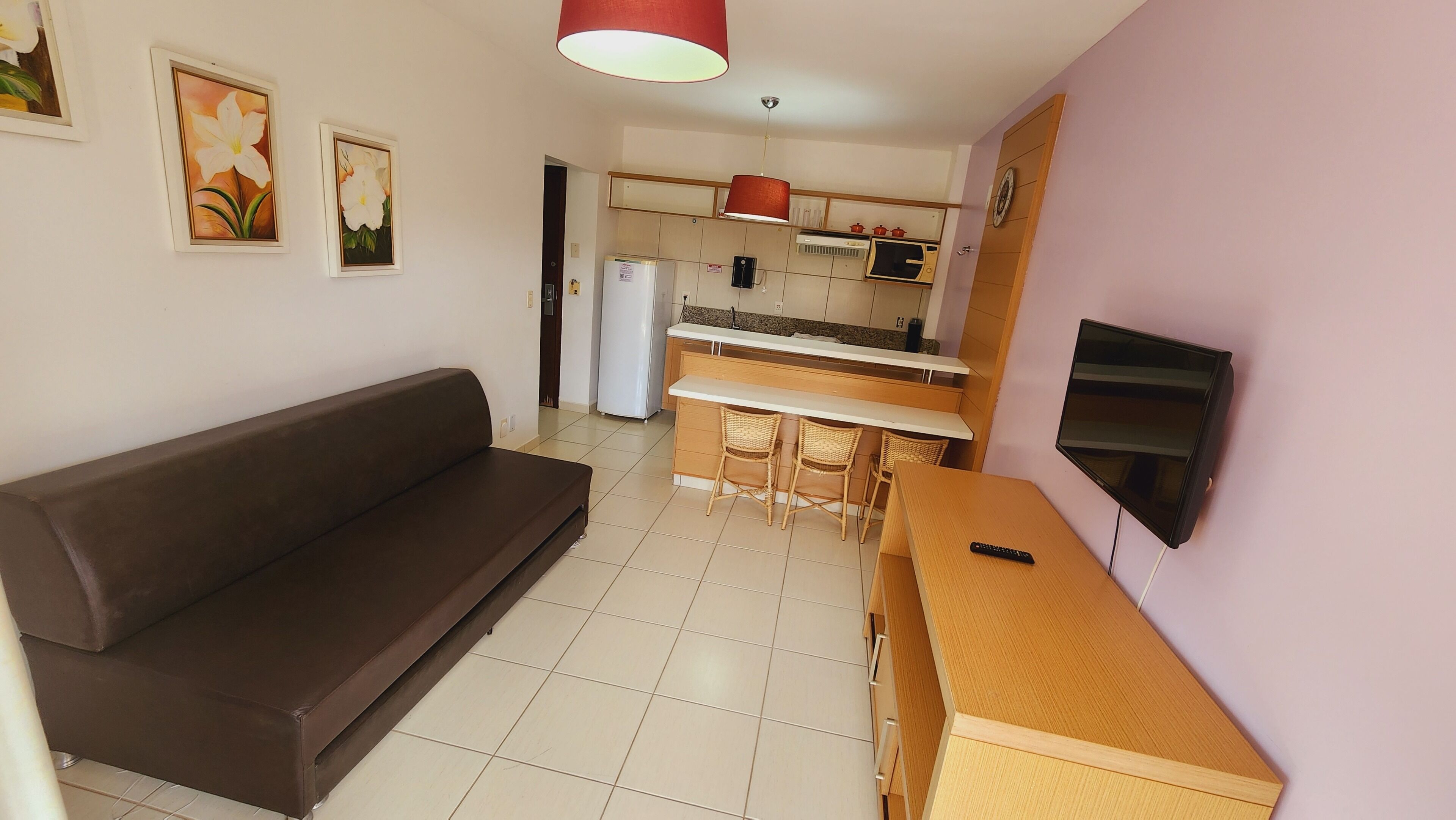 A compact living space with a sofa, a kitchenette, and a TV.