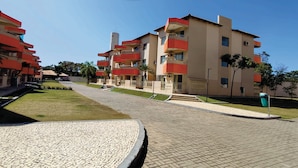 A residential building with multiple balconies, a paved walkway, and a small grassy area. - Náutico Flat Caldas Novas - HotFérias (Caldas Novas)