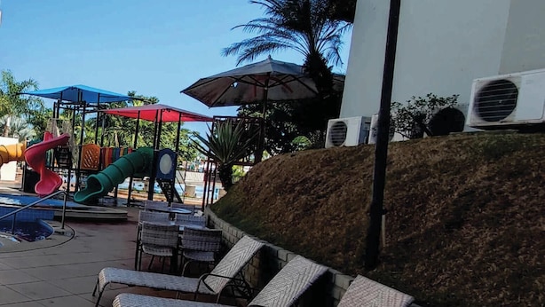 Outdoor lounge chairs, a children's play area, and a water slide. - Náutico Flat Caldas Novas - HotFérias (Caldas Novas)