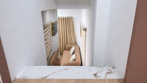 Un couloir étroit avec un lit, un radiateur et un rideau à rayures.