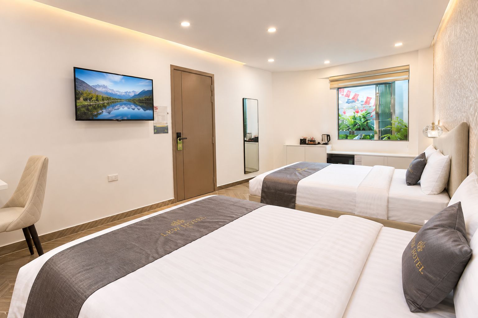 A hotel room with two beds, a television, a desk, and a window with a view.