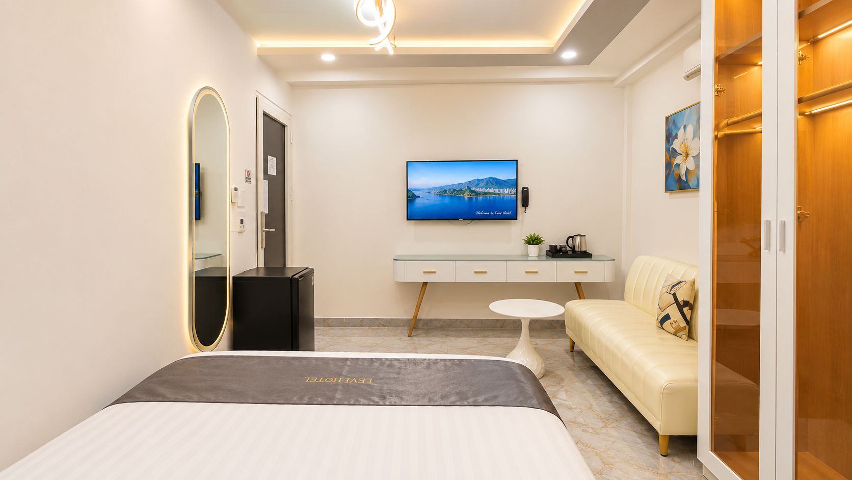 A hotel room with a bed, a desk, a sofa, a TV, and a wardrobe.