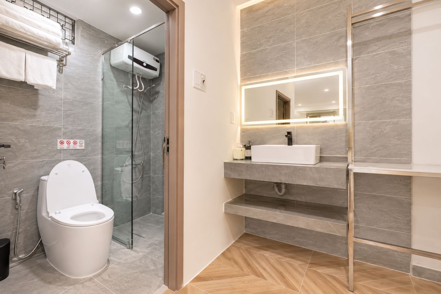 Un baño moderno con ducha envuelta en vidrio, inodoro blanco y tocador con espejo.