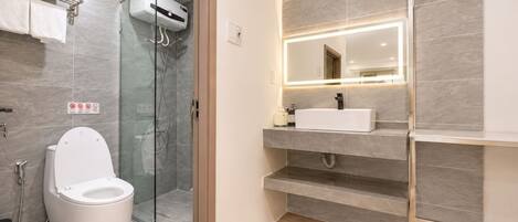 Un baño moderno con ducha envuelta en vidrio, inodoro blanco y tocador con espejo.