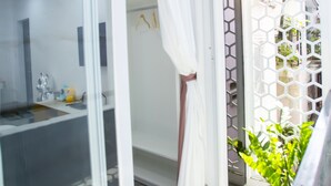 Une salle de bain avec une porte en verre, une douche et un rideau blanc.