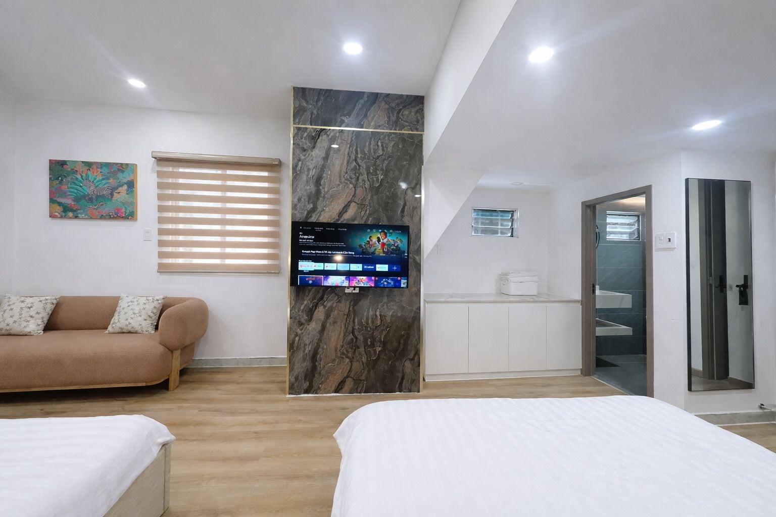 Een moderne hotelkamer met een flatscreen televisie, een bank, een bed en een badkamer.