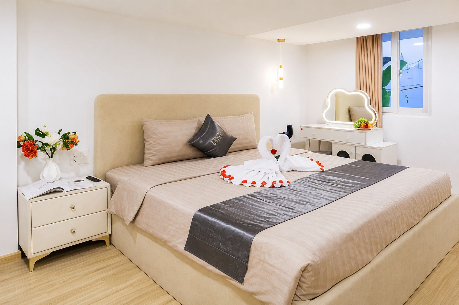 Une chambre d’hôtel avec un lit, une table de chevet, une lampe, un miroir et une fenêtre avec des rideaux.