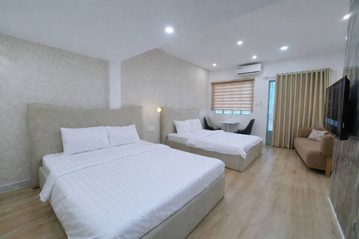 Ein Hotelzimmer mit zwei Betten, einem Fernseher, einem kleinen Tisch und einem Sofa.
