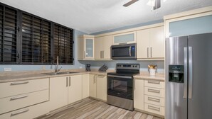 Una cocina moderna con armarios color beige, un refrigerador de acero inoxidable, un microondas y un horno.