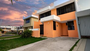 Un edificio residencial moderno con techo plano, ventanas amplias y un césped bien cuidado.