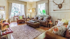 Ein stilvoll eingerichtetes Wohnzimmer mit Ledersofas, einem Kristalllüster und einer Dekoration aus Hirschschädeln.