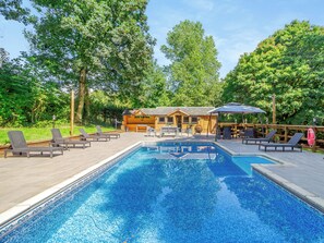 Ein Schwimmbad mit Liegestühlen, eine Holzhütte und eine Terrassenanlage.