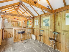 A rustic wooden interior with a bar area, stools, and artwork on the walls.