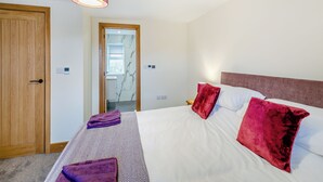 A hotel room with a bed, a wooden door, a bathroom with a mirror, and a ceiling light. - 2 bedroom accommodation in Risplith, near Ripon (Risplith, near Ripon)