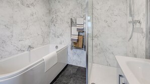 A modern bathroom with a marble wall, a bathtub, a shower, and a glass-enclosed shower area. - 2 bedroom accommodation in Risplith, near Ripon (Risplith, near Ripon)