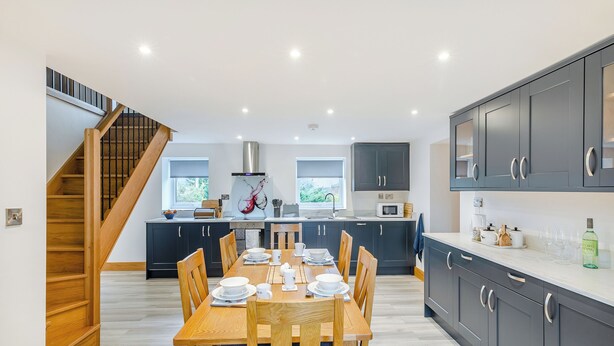 A modern kitchen with dark cabinets, a wooden dining table, and a staircase. - 2 bedroom accommodation in Risplith, near Ripon (Risplith, near Ripon)