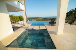 A swimming pool with a view of the ocean, lounge chairs, and a clear sky. - Casa Marlin Jaco -Completed 2024 (Hermosa)