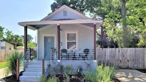 A single-story house with a front porch, a small garden, and a wooden fence.