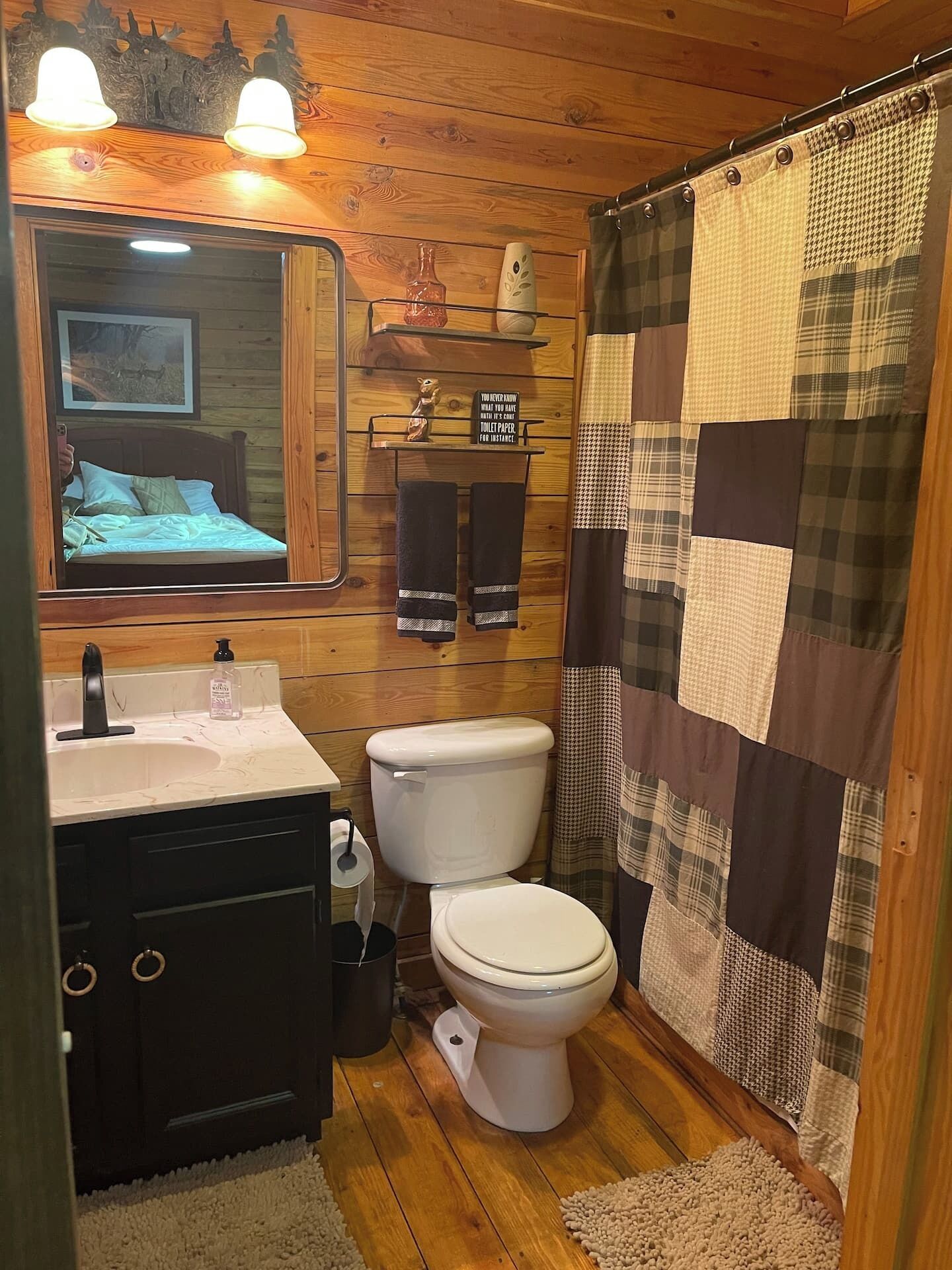 A bathroom with wooden walls, a sink, a toilet, and a shower curtain.