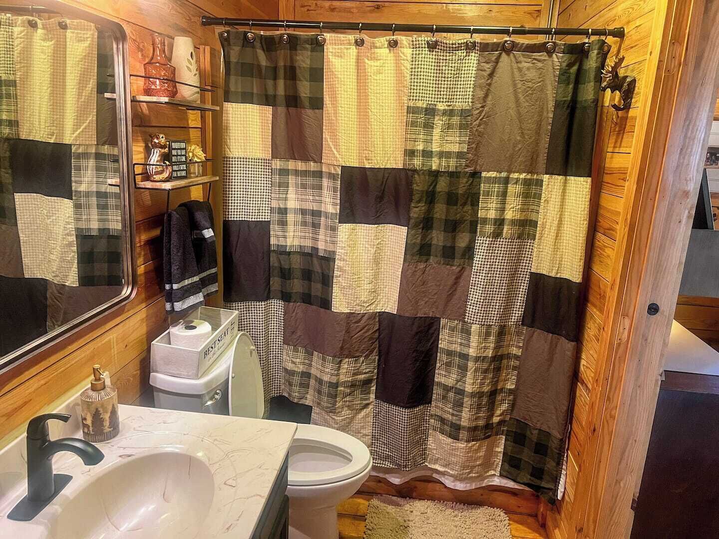 A bathroom with a patchwork shower curtain, a sink, and a toilet.