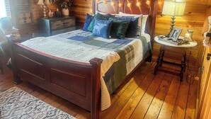 Ein Zimmer mit Holzwänden, einem Bett, einem Nachttisch, einem Spiegel und einem gerahmten Bild an der Wand.
