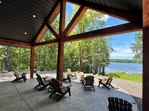 Un espacio al aire libre techado con sillas tipo Adirondack y vista a un lago.