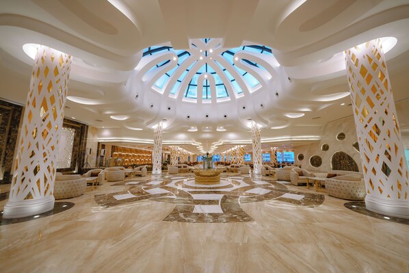 Enter a luxurious lobby with high ceilings, a skylight, and patterned flooring.