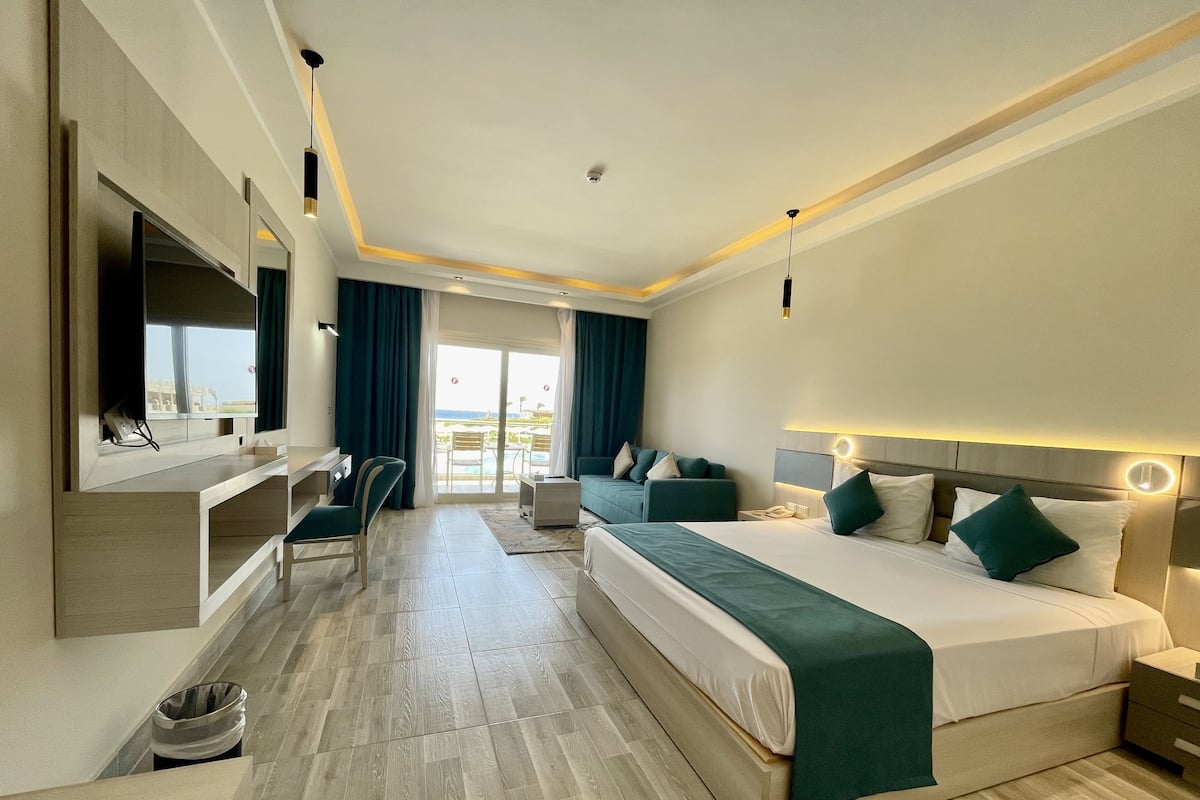 A modern hotel room with a large bed, a desk, and a TV.