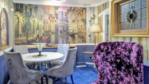 A room with a mural of a canal scene, a round table with chairs, and a purple velvet armchair. - 2 bedroom accommodation in Horning (Horning)