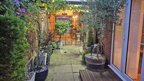 A narrow outdoor pathway flanked by potted plants and a wooden deck leading to a building entrance. - 2 bedroom accommodation in Horning (Horning)