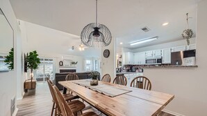 Una cocina moderna con armarios blancos, una mesa de comedor de madera y una lámpara colgante.