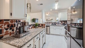 Una cocina moderna con armarios blancos, encimeras de granito y un salpicadero con diseños geométricos.