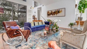 Een moderne woonkamer met een blauwe bank, een bruine leren fauteuil en een kamerkleed met dessin.