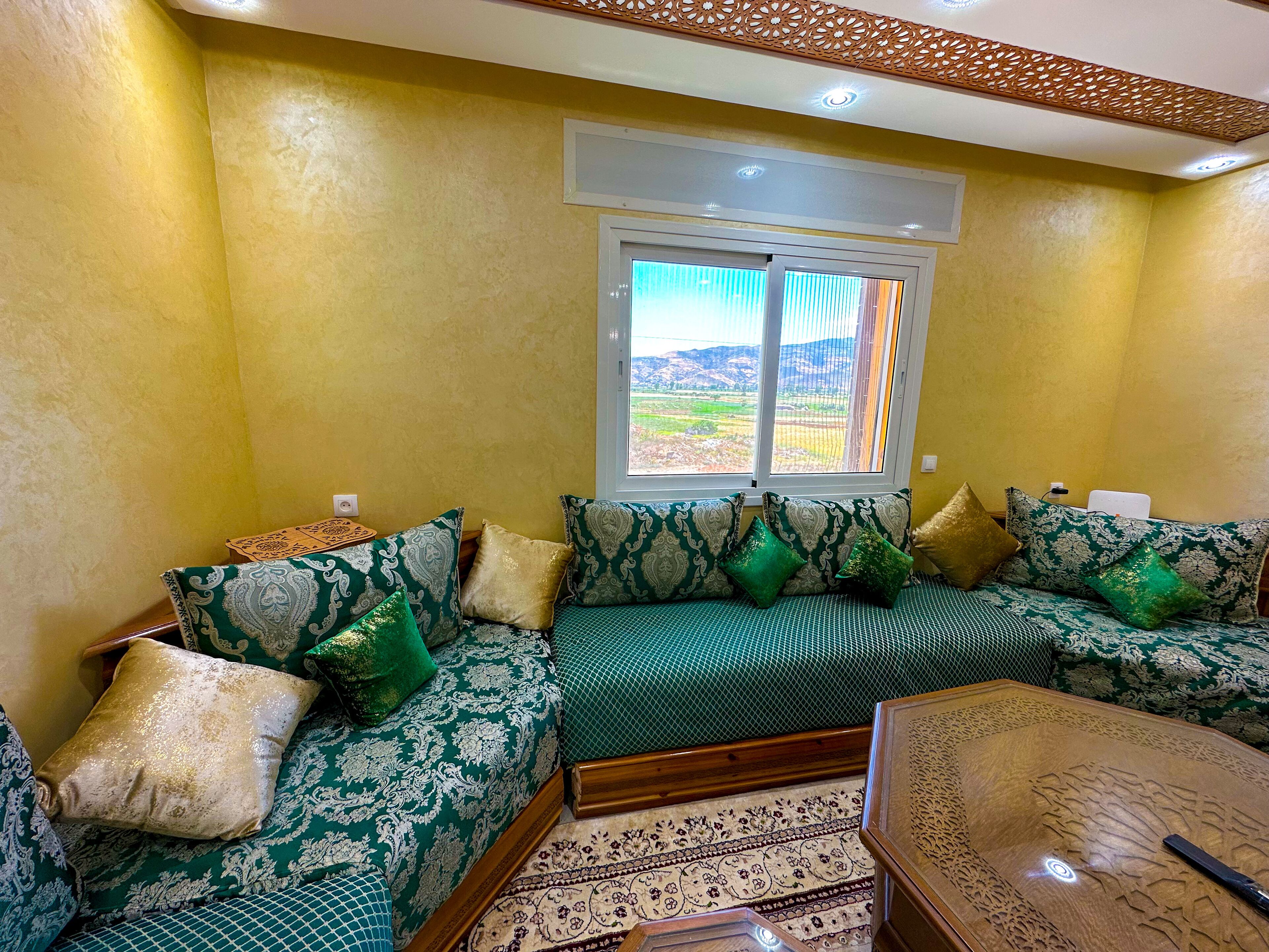 A living room with a sofa set, a coffee table, and a window with a view of the outdoors.