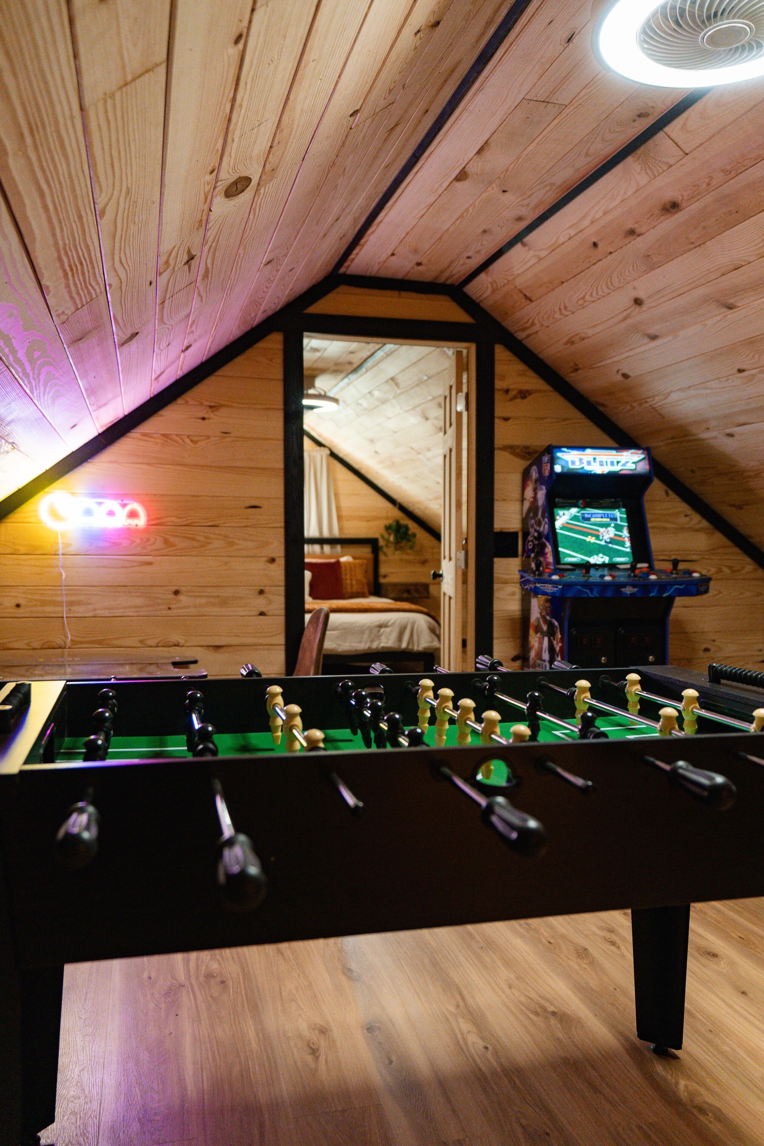 A foosball table in a room with wooden walls and a sloped ceiling.