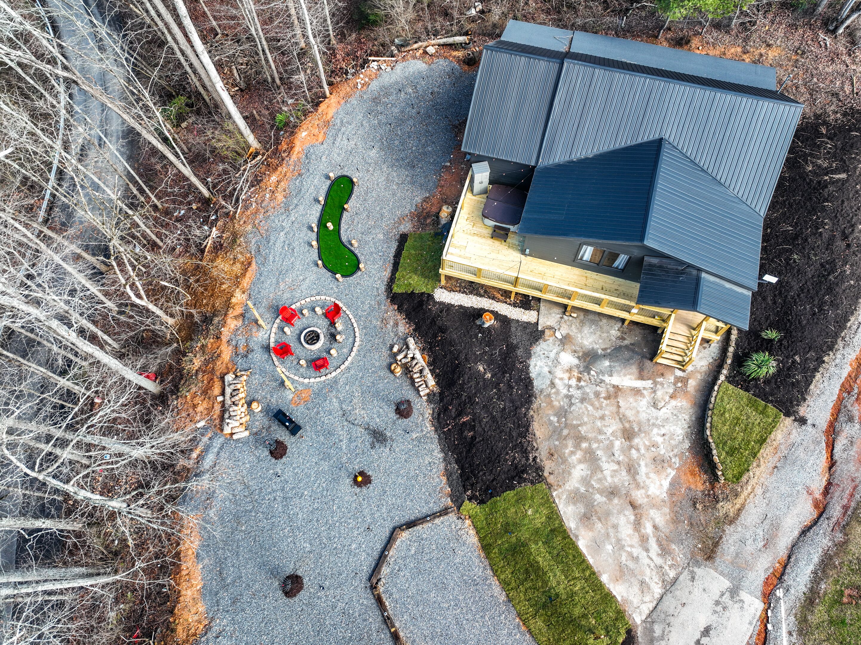 Una casa moderna con techo inclinado, un área de estar circular al aire libre y un pequeño jardín.