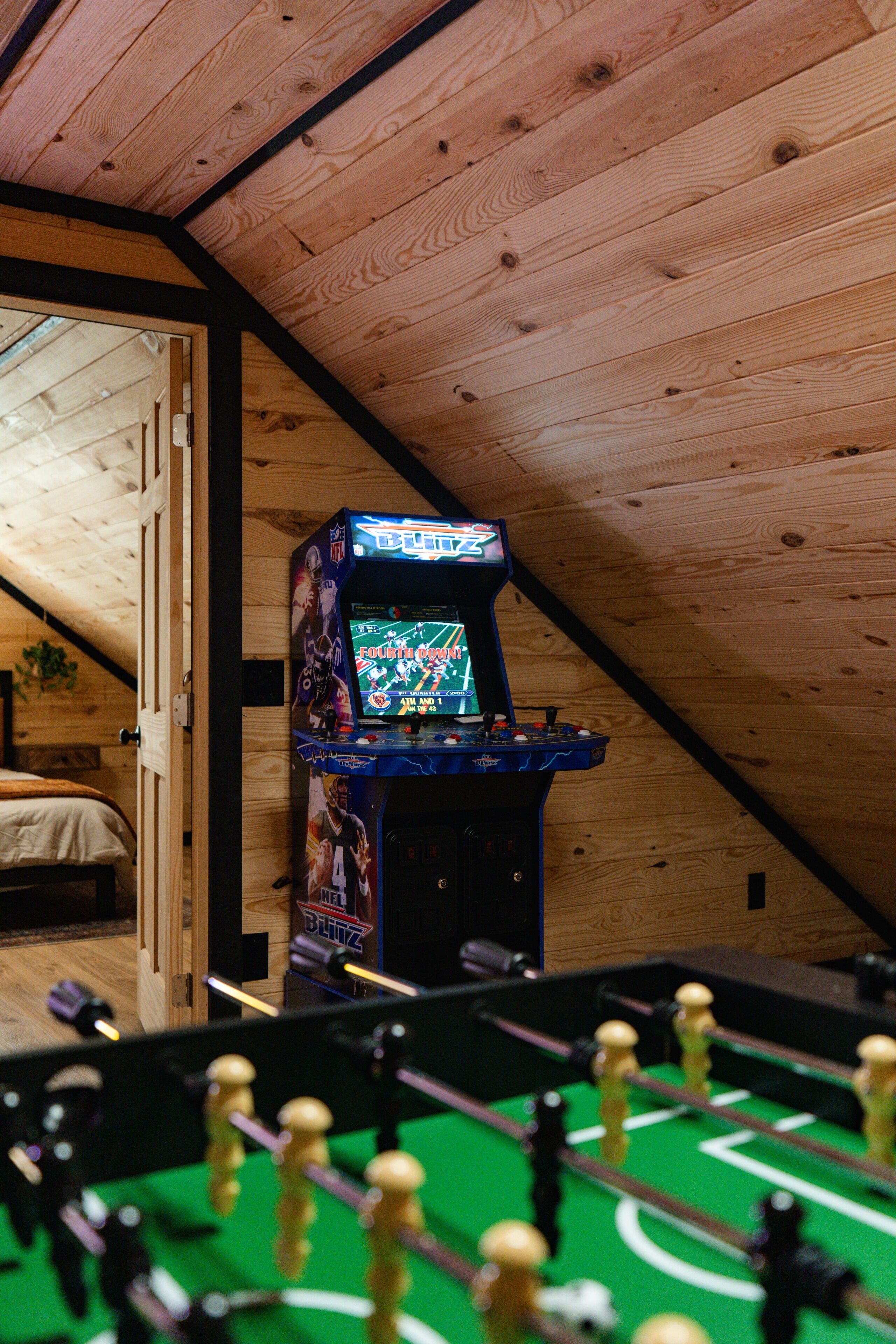 A room with a foosball table and a video game machine.