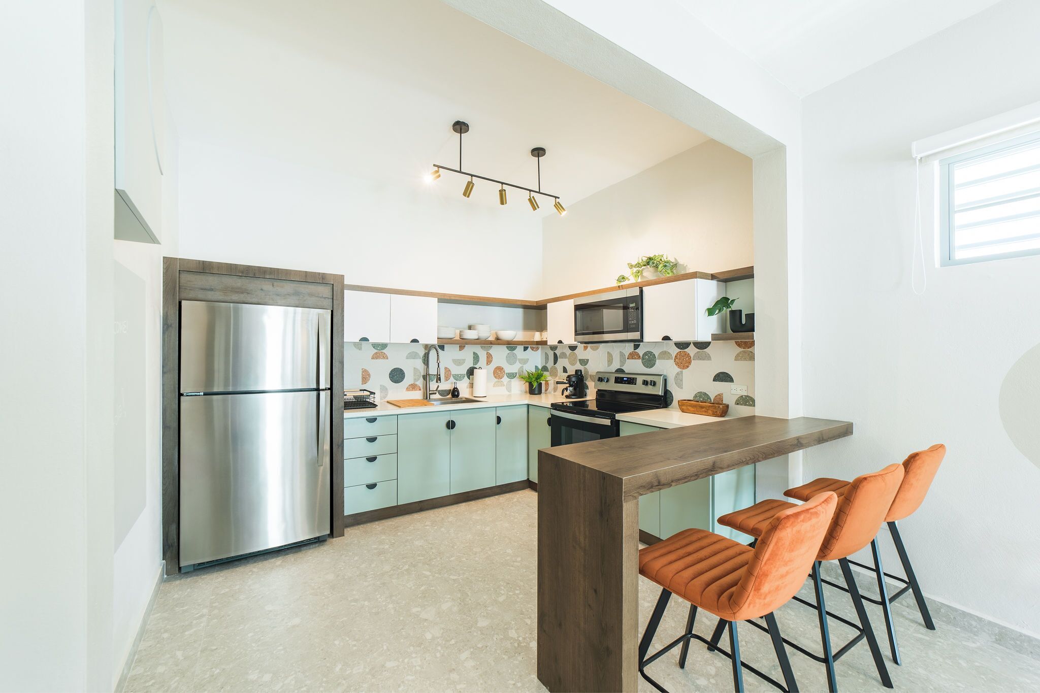 Een moderne keuken met een roestvrijstalen koelkast, een magnetron en een houten kookeiland met barkrukken.