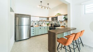 A modern kitchen with a stainless steel refrigerator, a microwave, and a wooden island with bar stools.