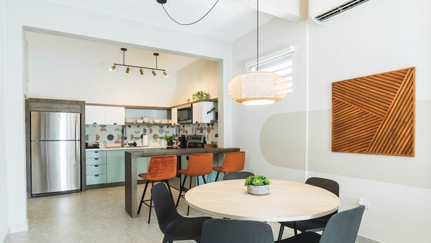 A modern kitchen with a central island, stainless steel appliances, and a dining area with a round table and chairs.